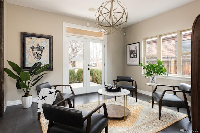 living area with an inviting chandelier, wood finished floors, french doors, and baseboards