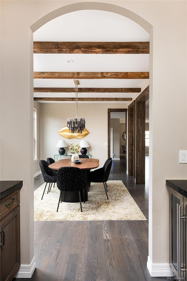 dining room featuring beamed ceiling, baseboards, dark wood-type flooring, and beverage cooler