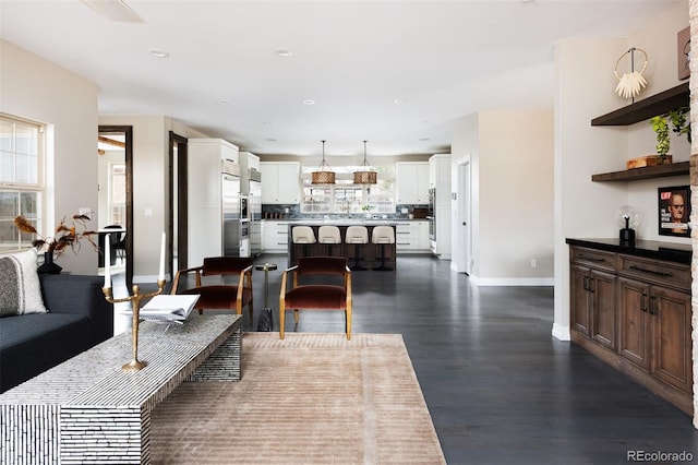 living area featuring a wealth of natural light, recessed lighting, baseboards, and dark wood-style flooring