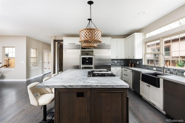 kitchen with gas cooktop, a healthy amount of sunlight, built in fridge, and a sink