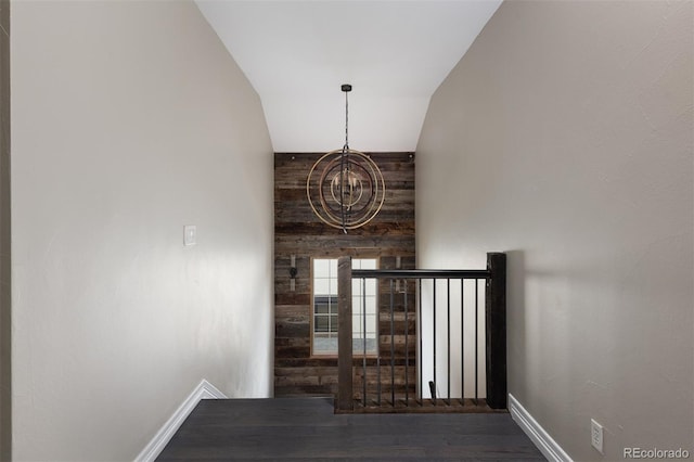 hall with wood finished floors, baseboards, and a chandelier