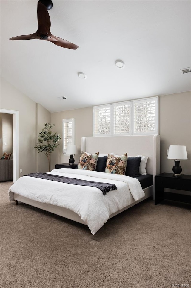 carpeted bedroom featuring visible vents, a ceiling fan, and vaulted ceiling