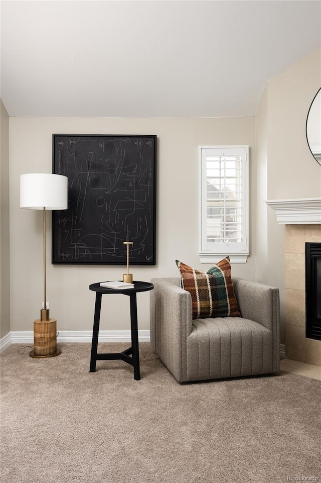 carpeted living area featuring a tile fireplace and baseboards