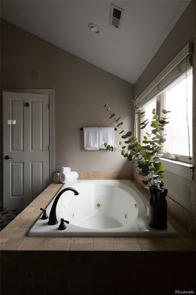 full bathroom featuring vaulted ceiling, a jetted tub, and visible vents