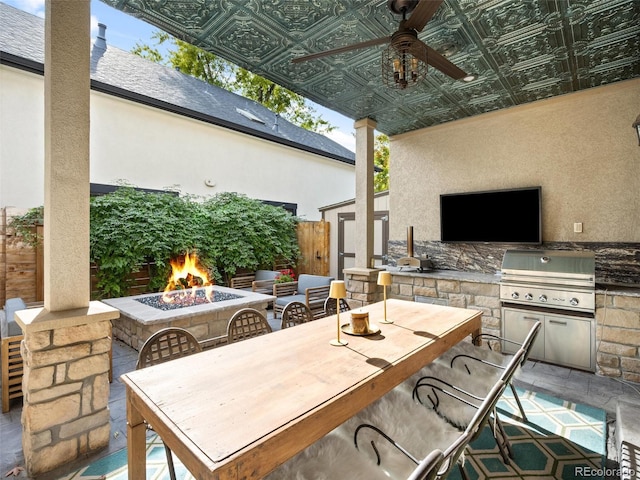 view of patio featuring area for grilling, outdoor dining area, a fire pit, and a lit fireplace