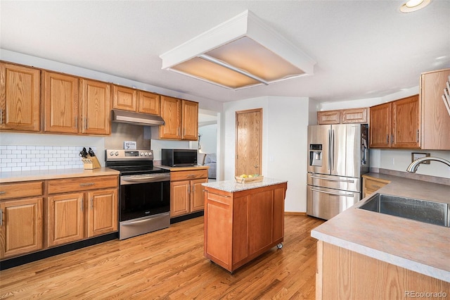 1325 Kingsfield St, Castle Rock, CO 80104 - kitchen with appliances with stainless steel finishes, under cabinet range hood, a sink, a center island, and light countertops