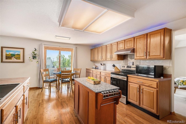 1325 Kingsfield St, Castle Rock, CO 80104 - kitchen featuring appliances with stainless steel finishes, under cabinet range hood, light wood-type flooring, a center island, and light countertops