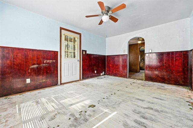 12 Marshall Pl, Longmont, CO 80504 - unfurnished room featuring arched walkways, a ceiling fan, wainscoting, hardwood / wood-style flooring, and wooden walls