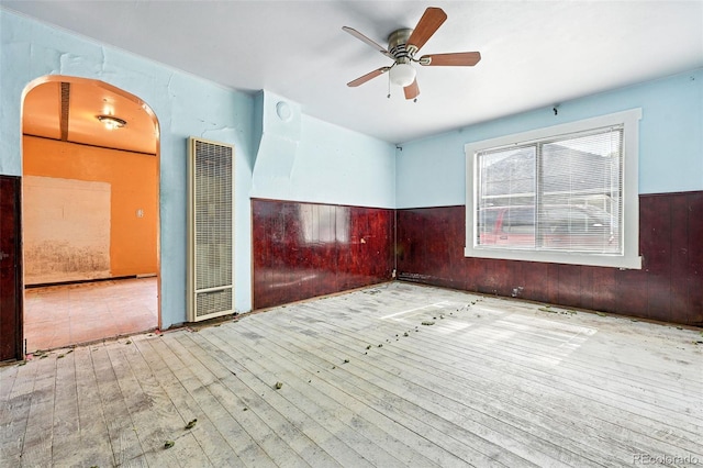 12 Marshall Pl, Longmont, CO 80504 - spare room featuring a heating unit, hardwood / wood-style floors, arched walkways, a ceiling fan, and wood walls