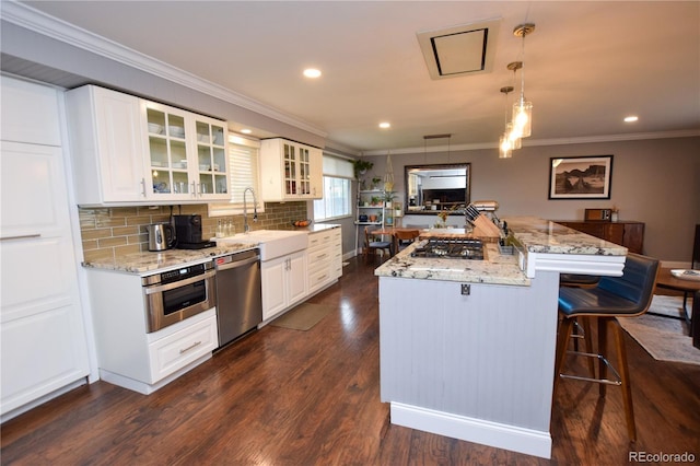 8229 Estes Ct, Arvada, CO 80005 - kitchen featuring stainless steel appliances, a kitchen bar, ornamental molding, light stone counters, and glass insert cabinets
