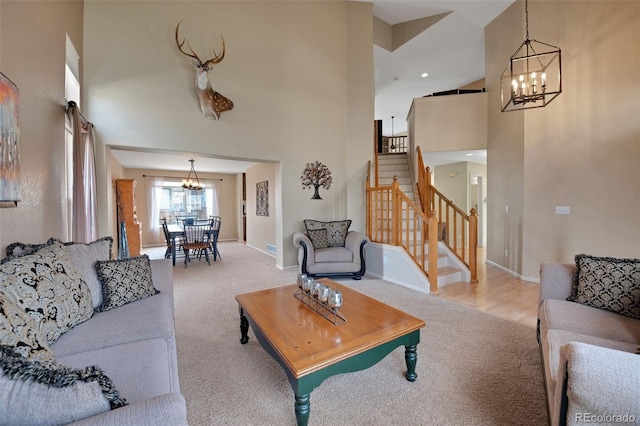 living room featuring a chandelier, light carpet, a high ceiling, stairs, and baseboards
