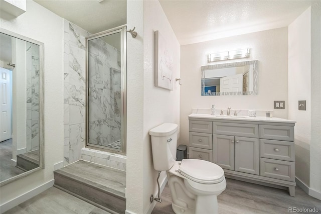 bathroom with vanity, toilet, wood finished floors, a marble finish shower, and baseboards