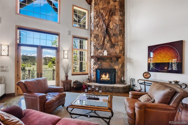 221 Columbine Pl, Woodland Park, CO 80863 - living area featuring a towering ceiling, wood finished floors, a stone fireplace, and french doors