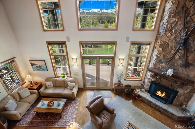 221 Columbine Pl, Woodland Park, CO 80863 - living room with wood finished floors, a fireplace, a high ceiling, and plenty of natural light