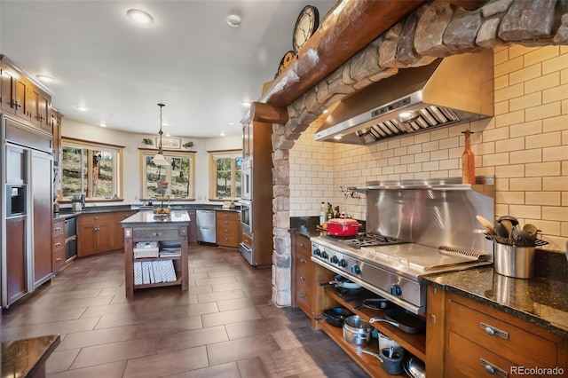 221 Columbine Pl, Woodland Park, CO 80863 - kitchen with appliances with stainless steel finishes, exhaust hood, brown cabinets, decorative backsplash, and recessed lighting