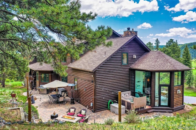 221 Columbine Pl, Woodland Park, CO 80863 - back of house with roof with shingles, a patio area, a chimney, log veneer siding, and a sunroom