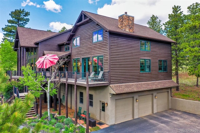 221 Columbine Pl, Woodland Park, CO 80863 - view of home's exterior with roof with shingles, log veneer siding, an attached garage, a chimney, and driveway