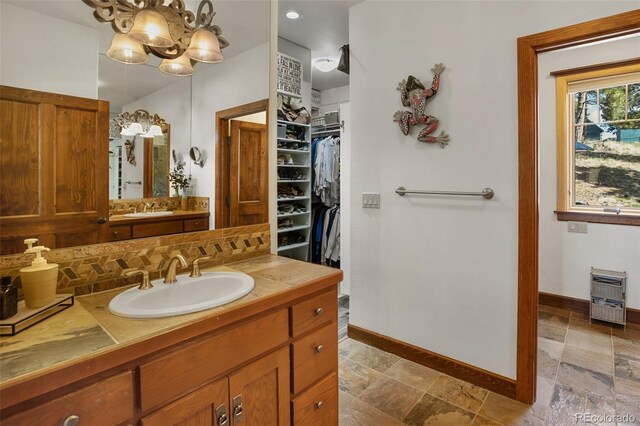 221 Columbine Pl, Woodland Park, CO 80863 - full bathroom featuring vanity, backsplash, stone tile floors, a walk in closet, and heating unit