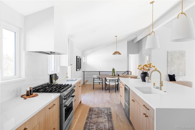 kitchen with high end stainless steel range, light wood-style flooring, light brown cabinets, a sink, and modern cabinets