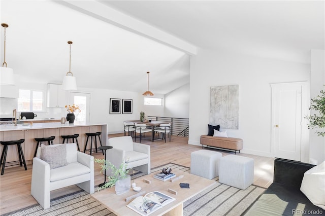 living room featuring vaulted ceiling with beams, baseboards, and light wood-style floors