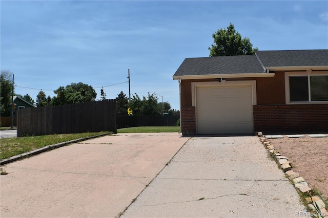 4585 Gatewood Dr, Colorado Springs, CO 80916 - view of side of home with driveway, brick siding, an attached garage, roof with shingles, and stucco siding