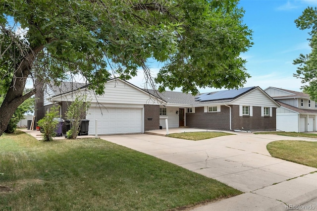 ranch-style house featuring solar panels, a garage, and a front yard