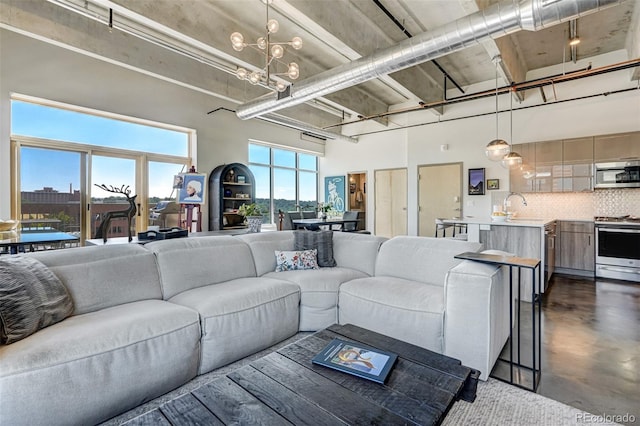 living room with a notable chandelier, a high ceiling, and sink