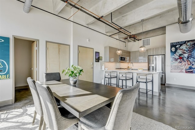 dining area with a high ceiling, sink, and concrete floors