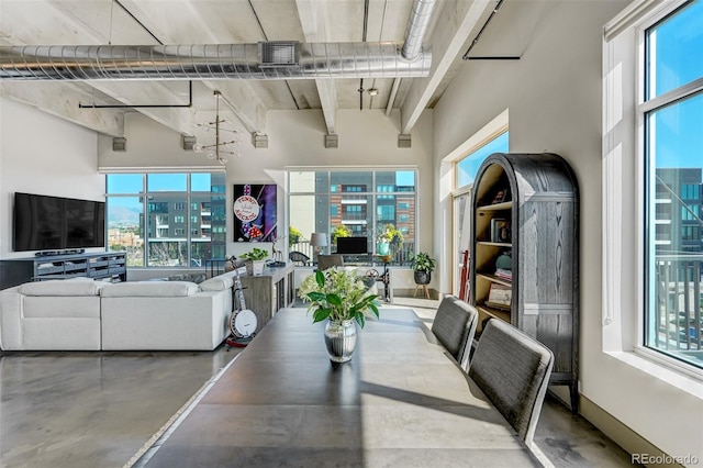 dining space featuring a high ceiling, concrete floors, and plenty of natural light