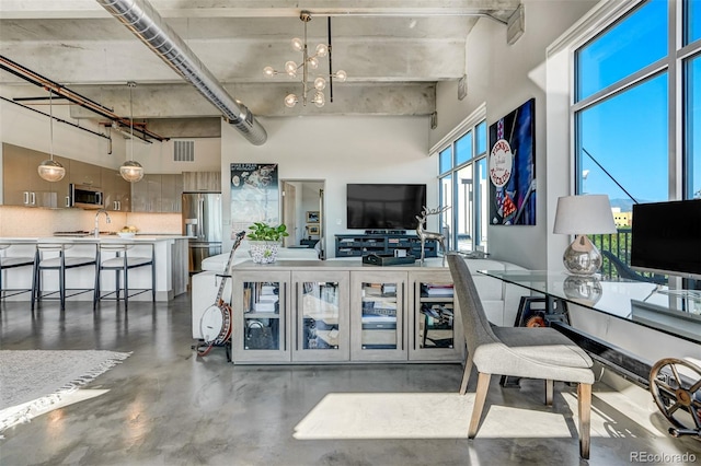 interior space featuring a high ceiling, concrete flooring, a chandelier, and sink