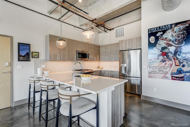 kitchen featuring hanging light fixtures, kitchen peninsula, gray cabinets, stainless steel appliances, and a kitchen bar