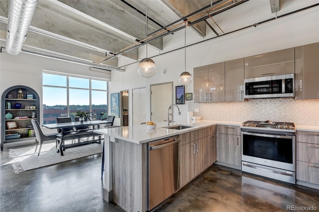 kitchen featuring stainless steel appliances, backsplash, decorative light fixtures, and sink