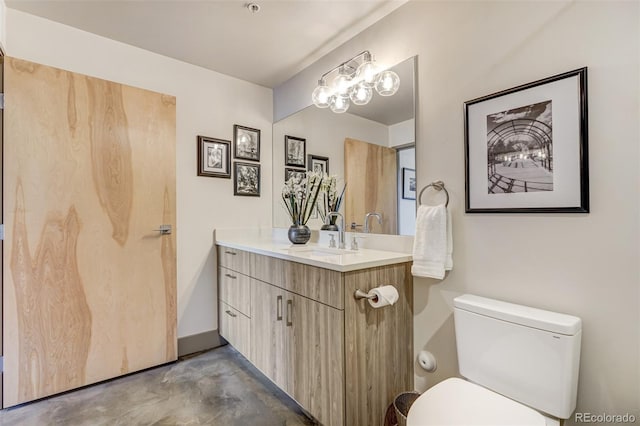 bathroom with concrete flooring, vanity, and toilet