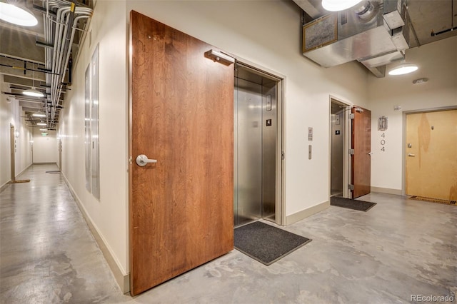 corridor with concrete flooring and elevator