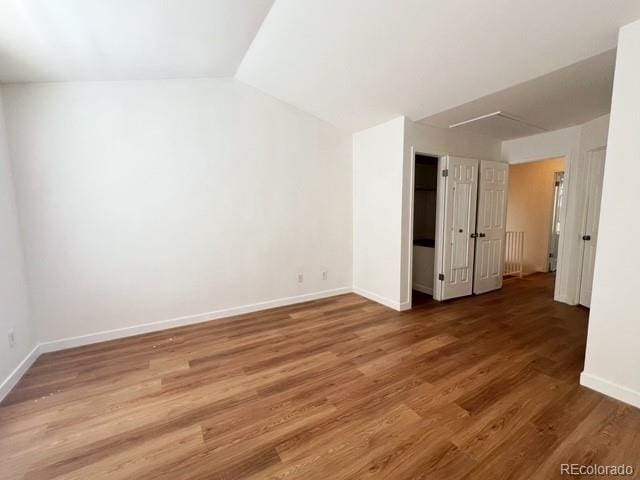 interior space featuring baseboards, vaulted ceiling, and wood finished floors