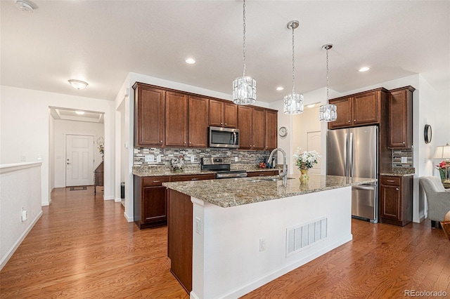11791 Barrentine Loop, Parker, CO 80138 - kitchen featuring stainless steel appliances, a sink, dark wood-style flooring, decorative backsplash, and light stone counters