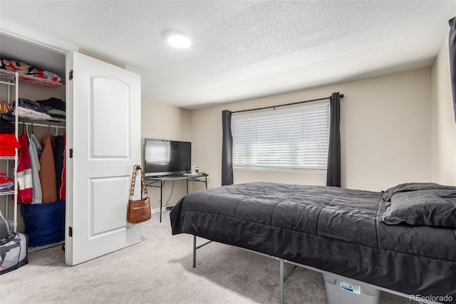 bedroom with a textured ceiling, a spacious closet, a closet, and carpet flooring