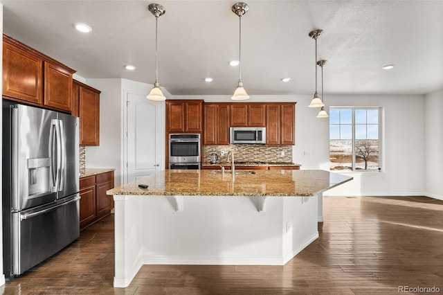 kitchen featuring a breakfast bar, decorative light fixtures, decorative backsplash, stainless steel appliances, and a center island with sink