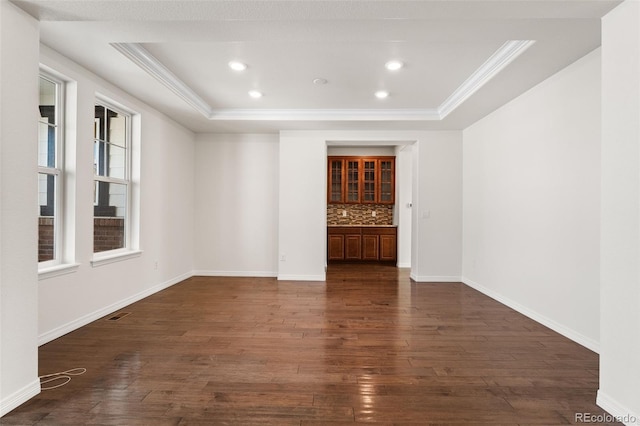 spare room with dark wood-type flooring, ornamental molding, and a raised ceiling