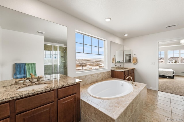 bathroom featuring tiled tub, vanity, and tile patterned floors