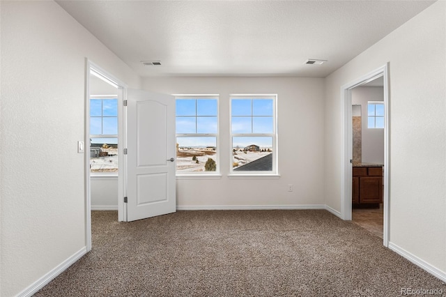 unfurnished bedroom with a water view, carpet floors, connected bathroom, and a textured ceiling