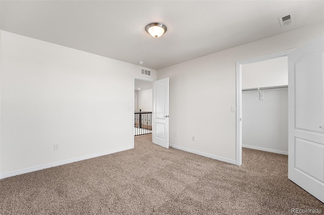 unfurnished bedroom with a closet, carpet flooring, and a spacious closet