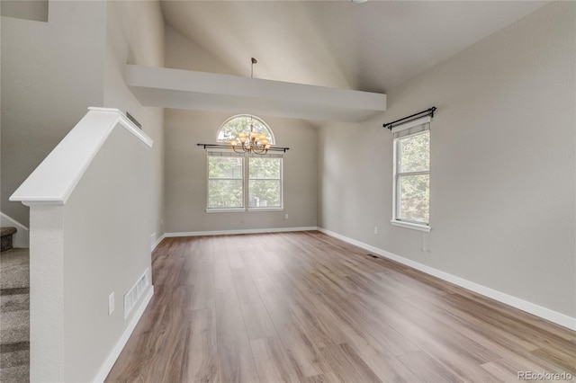 6735 W 97th Cir, Westminster, CO 80021 - empty room featuring a chandelier, plenty of natural light, wood finished floors, stairway, and high vaulted ceiling