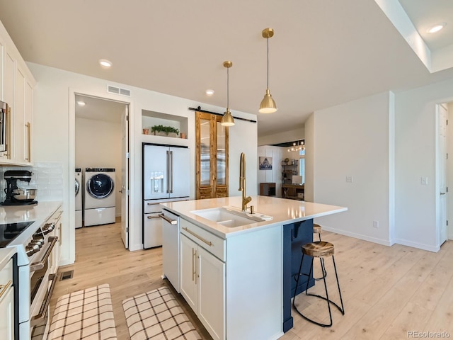 kitchen featuring white cabinetry, sink, a kitchen island with sink, and independent washer and dryer