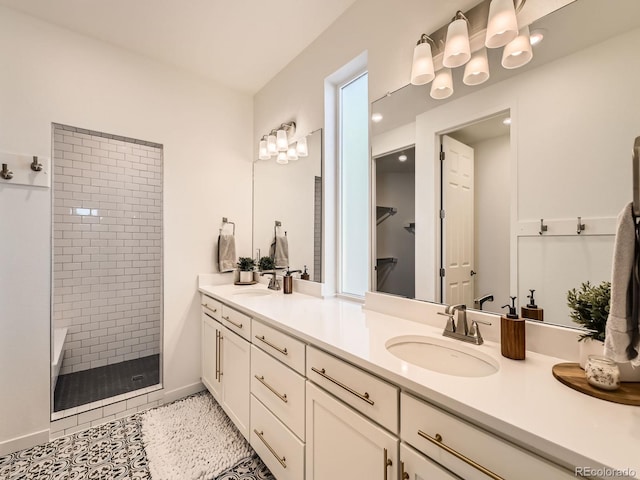 bathroom with tile patterned flooring, vanity, and a tile shower