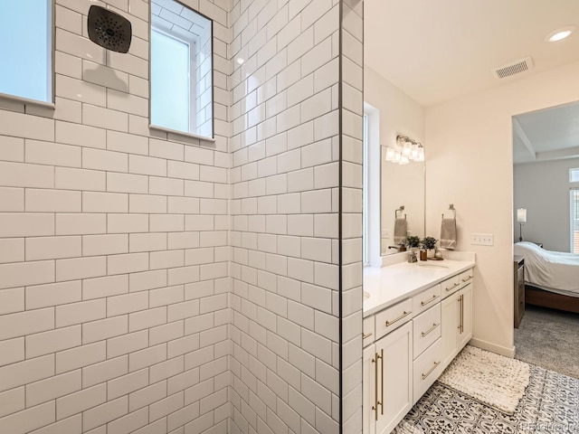 bathroom with a tile shower, a wealth of natural light, and vanity