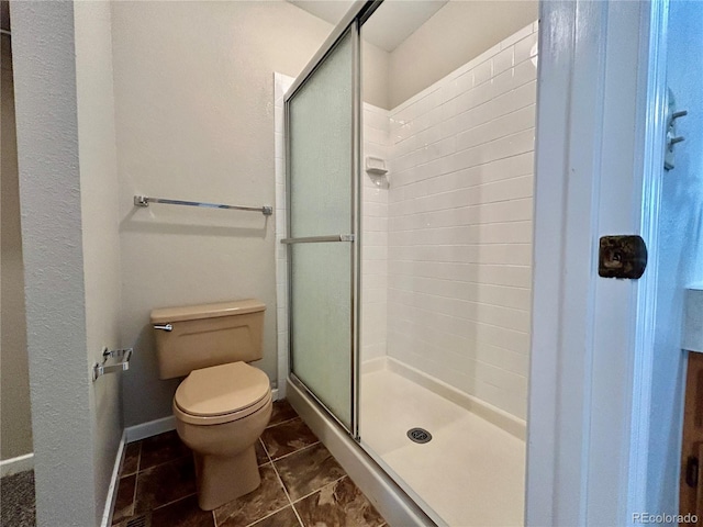 bathroom featuring toilet, tile patterned floors, and a shower with door