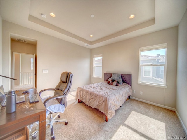 bedroom with a tray ceiling and light colored carpet