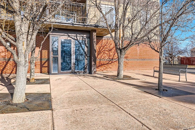 property entrance featuring brick siding, fence, and a balcony