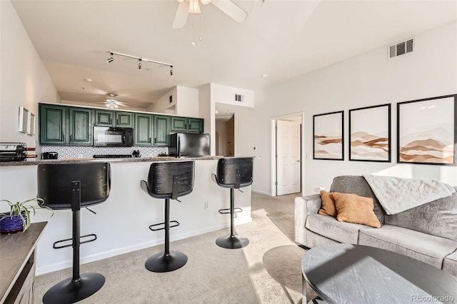 kitchen featuring a ceiling fan, track lighting, black appliances, lofted ceiling, and green cabinetry